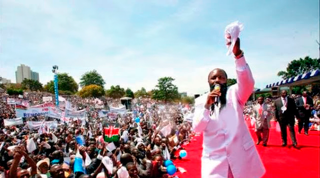 Dr. David Owuor pregando em uma cruzada ao ar livre diante de uma multidão